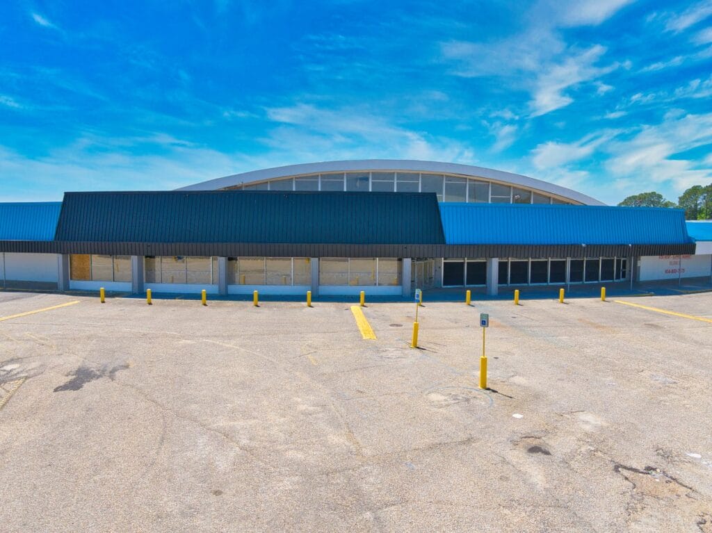 A modern shopping center with various storefronts and a clear blue sky, showcasing the Normendale Shopping Center.