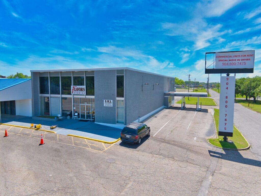 Exterior view of Normendale Shopping Center showcasing various storefronts and a clear blue sky.