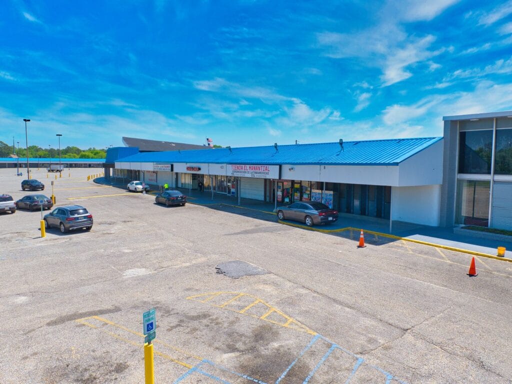 Exterior view of Normendale Shopping Center featuring a variety of storefronts and ample parking space.