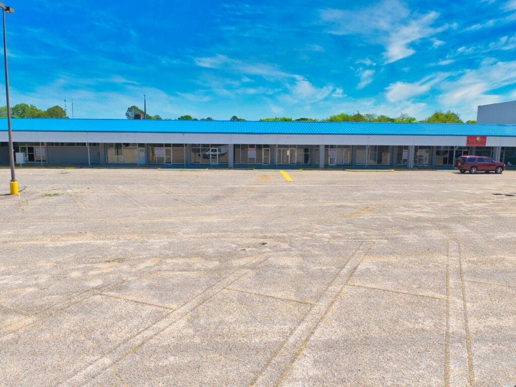 A modern shopping center with various storefronts and a clear blue sky, showcasing the Normendale Shopping Center.