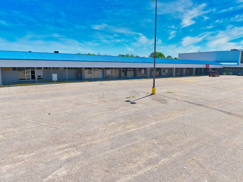 Exterior view of Normendale Shopping Center showcasing storefronts and parking area, ideal for shopping and dining.