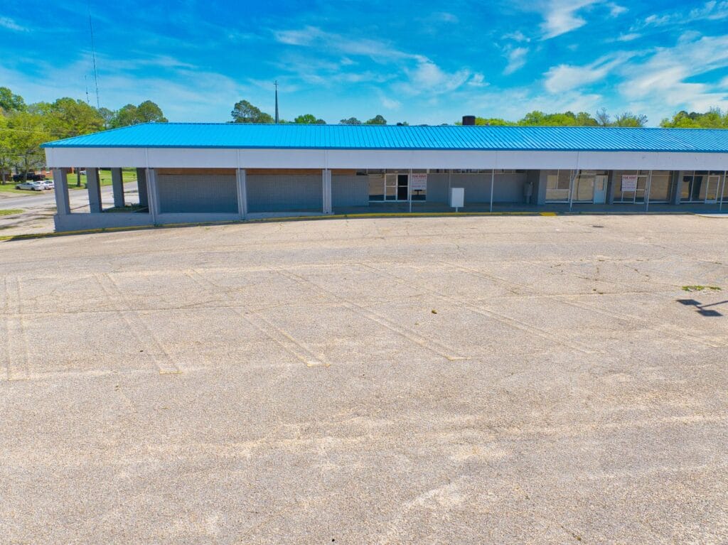 A shopping center featuring multiple storefronts, ample parking, and clear signage, ideal for local businesses.