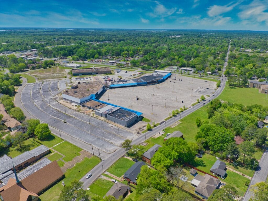 A modern shopping center with various storefronts and a clear blue sky, showcasing the Normendale Shopping Center.