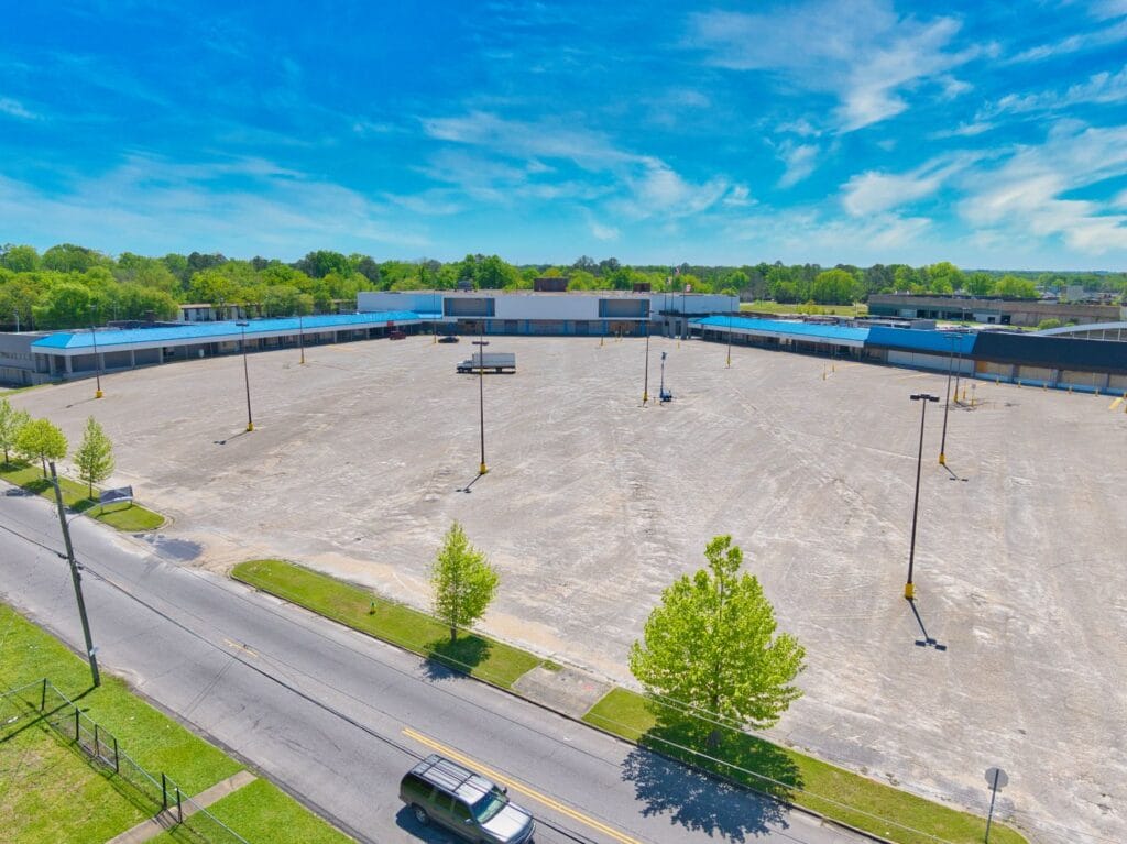 A vibrant shopping center with various storefronts and a clear blue sky, showcasing the Normendale Shopping Center.