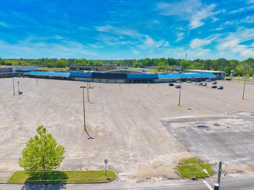 A view of Normendale Shopping Center featuring a variety of storefronts and parking spaces under a clear blue sky.
