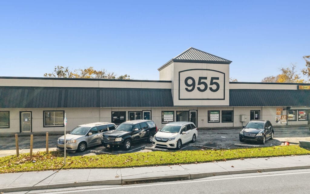 Exterior view of the Orange Shopping Center in Daytona Beach, showcasing storefronts and parking area.