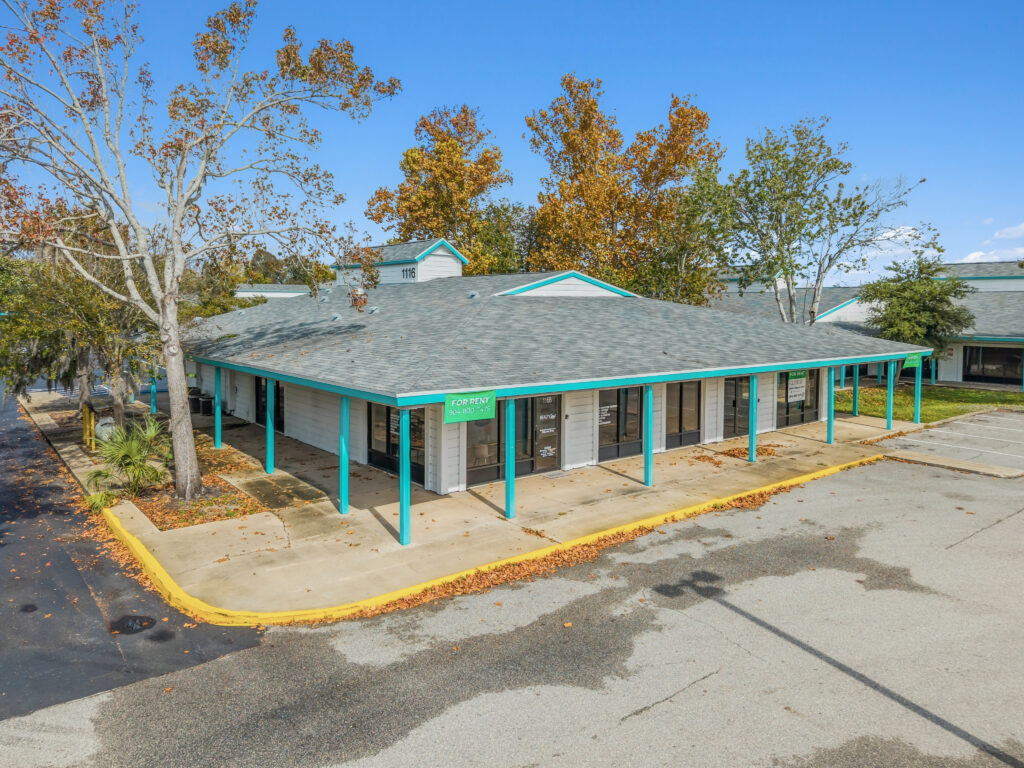 A spacious commercial property at 1128 Beville Rd, Daytona Beach, featuring a modern facade and ample parking.