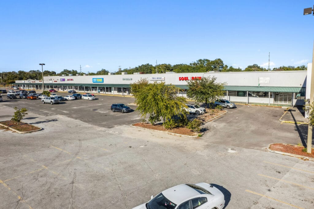 Exterior view of a commercial property at 5451 Norwood Ave, Jacksonville, featuring a large parking lot and signage.