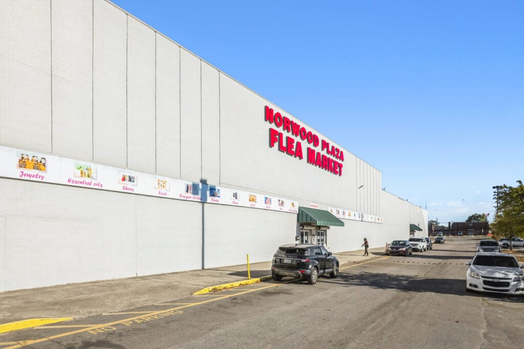 Exterior view of Norwood Plaza Flea Market in Jacksonville, showcasing vibrant signage and a busy parking area.