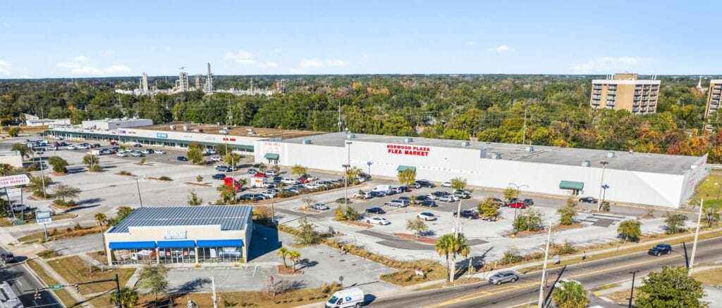Exterior view of Norwood Plaza Flea Market with colorful signage and a busy parking lot, showcasing a vibrant shopping atmosp