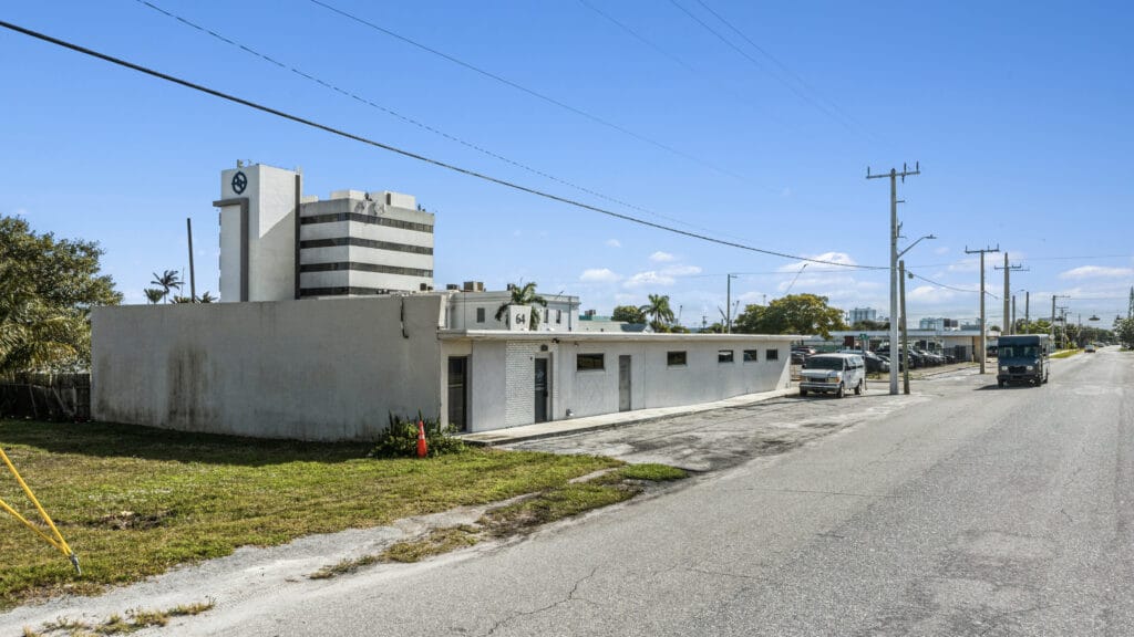 Exterior view of a residential property at 64 W 21st St, Riviera Beach, showcasing a well-maintained lawn and driveway.